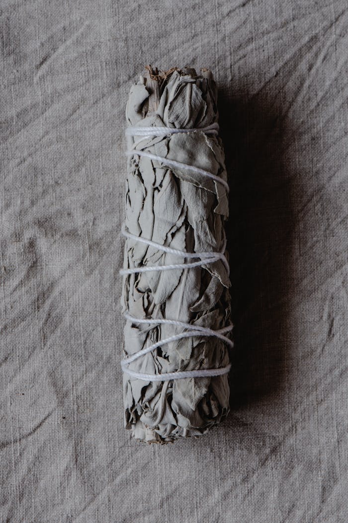 White sage smudge stick on rustic cloth backdrop, ideal for spiritual and purification themes.